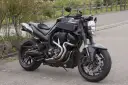 Czarny Yamaha MT-01 z customowym wydechem i sportowymi dodatkami, gotowy na jazdę po krętych drogach.