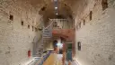 Wnętrze restauracji Srebrna Góra z kamiennymi ścianami, kręconymi schodami i drewnianymi stołami.