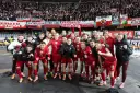 Radosna me grupa polska w czerwonych strojach świętuje z kibicami.