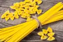 Makaron z mąki durum i zwykłej pszennej. Farfalle i spaghetti na drewnianym tle.