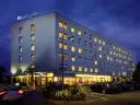 Ibis Budget Warszawa Centrum nocą. Hotel z podświetlanym logo, oknami i parkingiem.