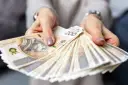 Dłonie trzymające plik banknotów 200 zł. Pytanie o to, ile zarabia hotelarz, często wiąże się z takimi widokami.