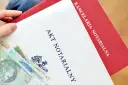 Akt notarialny z widocznymi banknotami. Kancelaria notarialna przygotowuje dokumenty, a taksa notarialna jest częścią kosztów.