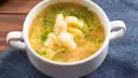 Aromaticzna zupa zacierkowa z koperkiem, podana w białej miseczce na granatowym obrusie.