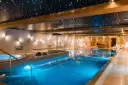 Basen w hotelu SPA z podświetlanym sufitem imitującym gwiazdy i błękitną wodą.