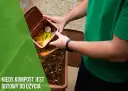 Mężczyzna dodaje resztki organiczne do kompostownika, tworząc cenną ziemię kompostową.