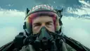 Tom Cruise jako Maverick w hełmie z napisem "MAVERICK" w filmie Top Gun: Maverick. Intensywne spojrzenie pilota w kokpicie myśliwca.