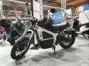 Elegancki motocykl elektryczny Horwin CR6, idealny do zdobycia prawa jazdy na motocykl. W tle inne skutery elektryczne.