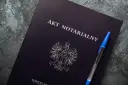 Na ciemnogranatowej okładce widnieje napis "AKT NOTARIALNY" i godło Polski. Obok leży niebieski długopis.