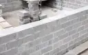 Budowa fundamentów z bloczków betonowych, stosy bloczków na placu budowy.