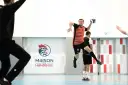Piłkarz ręczny, niczym szczypiornista, wyskakuje do rzutu. W tle logo "Maison du Handball".