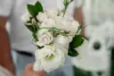 Delikatny bukiet z jednego kwiatu, otoczony pąkami róż i zielonymi liśćmi, tworzy romantyczną kompozycję.