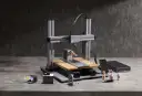 Drukarka 3D CNC z akcesoriami i wydrukowanymi figurkami.