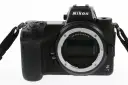 Czarny aparat Nikon Z7 III z obiektywem bez obiektywu, widoczny z przodu, z paskiem na nadgarstek.