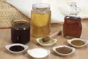 Domowy syrop cukrowy i kupny syrop barmański obok miodu i cukru.