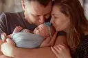 Rodzice całują śpiące maleństwo. Serdeczne gratulacje z okazji narodzin córeczki!