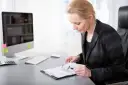 Kobieta z lupą analizuje dokument, zastanawiając się, ile zarabia recepcjonista.