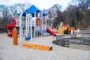 Nowoczesny plac zabaw z piaskownicą, zjeżdżalniami i domkiem dla dzieci.