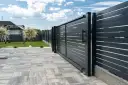 Solidny fundament pod bramę przesuwną zapewnia jej stabilność i płynne działanie. Nowoczesna, ciemnoszara brama z poziomymi lamelami.