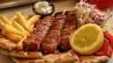 Pyszne souvlaki na patykach, podane z frytkami, pitą, surówką i cytryną.