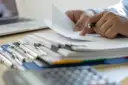 Ręce przeglądają dokumenty, szukając informacji, kiedy można wymeldować członka rodziny.