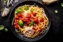 Talerz spaghetti z sosem pomidorowym, parmezanem i bazylią.