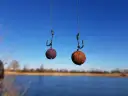 Dwa czeskie kulki proteinowe wiszą na haczykach nad wodą, gotowe do połowu.