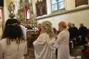 Uroczystość w kościele. Kobieta w białej sukni, z kwiatami we włosach, klęczy. To moment konsekracji, ważny dla dziewicy konsekrowanej.