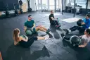 Fünf Personen machen im Fitnessstudio Sit-ups mit Medizinbällen.