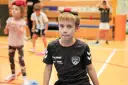 Chłopiec z zabawką na głowie, w koszulce KS Bysstra, podczas zajęć sportowych.