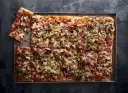 Oto najlepsza pizza przepis: prostokątna, obficie posypana pieczarkami, szynką i oliwkami, z ciągnącym się serem.