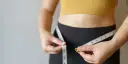 Kobieta mierzy talię centymetrem. Dowiedz się, jak podkręcić metabolizm po 40. i odzyskać formę.