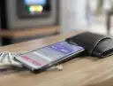 Smartfon z aplikacją BLIK, obok portfel i banknoty na drewnianym stole.