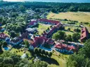 Widok z lotu ptaka na kompleks budynków hotelowych z czerwonymi dachami. Wiele pozytywnych kadyny folwark hotel & spa opinie potwierdza urok tego miejsca.