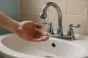 Dłoń łapie kropelki wody z kranu. Woda ledwo kapie, zastanawiam się, ile bar ma woda w kranie.