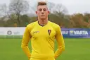 Młody bramkarz Michał Hoffmann w żółtej koszulce z herbem Pogoni.