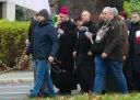 Grupa mężczyzn, w tym biskup, idzie ulicą. Niektórzy niosą różańce, jak rycerze Maryi.