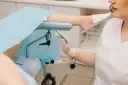 Lekarz przygotowuje się do pobrania wymazu do gbs badanie. Pacjentka leży na fotelu ginekologicznym.