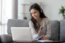 Kobieta w słuchawkach pracuje przy laptopie, tworząc komfortowy **home office**.