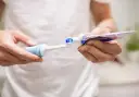 Przygotowanie do mycia zębów szczoteczką soniczną: nakładanie pasty na główkę.