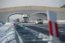 Autostrada A2 z mostem nad jezdnią, jadące samochody i ciężarówki w zimowej scenerii.