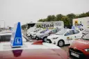 Auta szkoleniowe z literą "L" na dachu, gotowe do nauki różnych kategorii prawa jazdy.