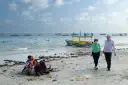 Spacerowery na plaży w Somalii, z łodziami na morzu. Czy Somalia jest bezpieczna? Turyści spacerują, podczas gdy lokalni mieszkańcy odpoczywają na piasku.
