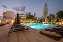 Basen hotelowy oświetlony nocą, leżaki i palmy. Idealne miejsce na relaks, zgodnie z licznymi heronissos hotel opinie.