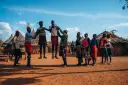 Ludzie w tradycyjnych strojach tańczą przed chatami. Czy Uganda jest bezpiecznie? Tak, w takich miejscach można poczuć się bezpiecznie.