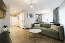 Nowoczesny apartament suite, z wygodną kanapą, stolikiem kawowym i widokiem na kuchnię.