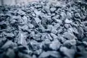 Głęboki, szary żwir do betonu, ułożony w dużą hałdę. Kamienie są ostre i nieregularne, tworząc teksturę idealną do budowy.