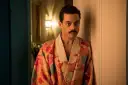 Freddie Mercury w barwnym szlafroku, jakby zrodzony z **bohemian rhapsody**, opiera się o drzwi.