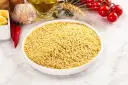 Miseczka pełna makaronu orzo, idealnego do przygotowania pysznego dania. Obok czosnek, papryczki chili, pomidorki i oliwa.