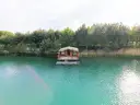 Drewniana chata na wodzie, otoczona lasem, unosi się na turkusowym zalewie.